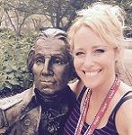 Nicole Weaver smiling looking at the camera sitting next to a GW statue